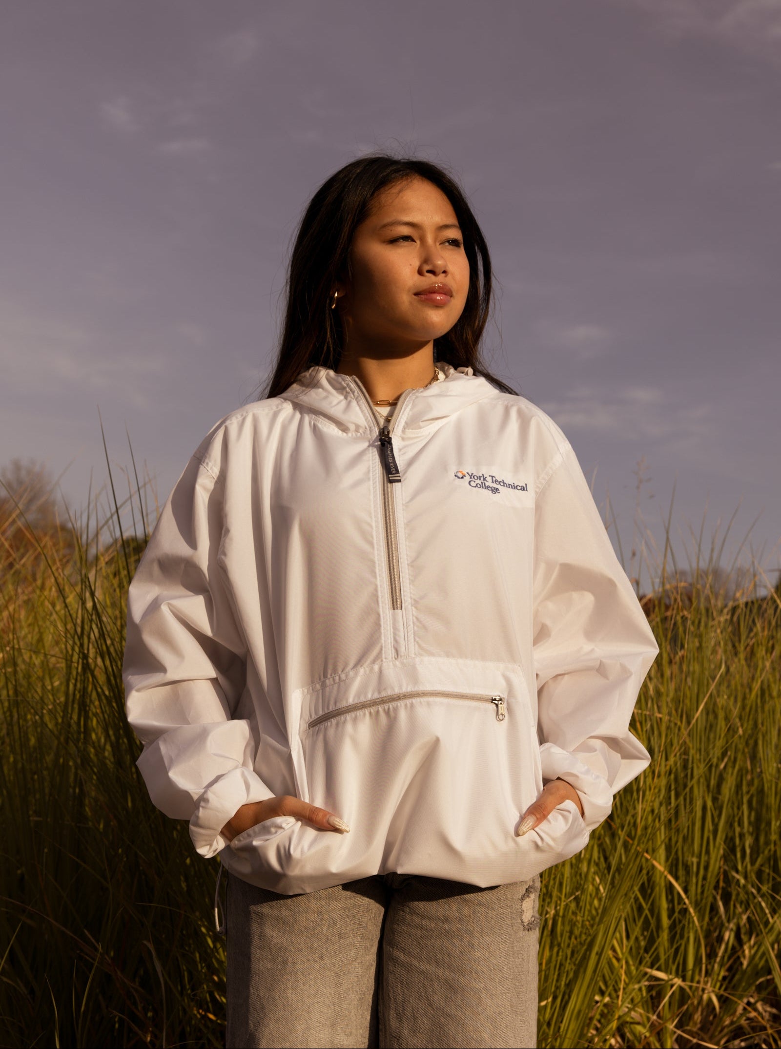 Person wearing a white jacket with a logo in a field